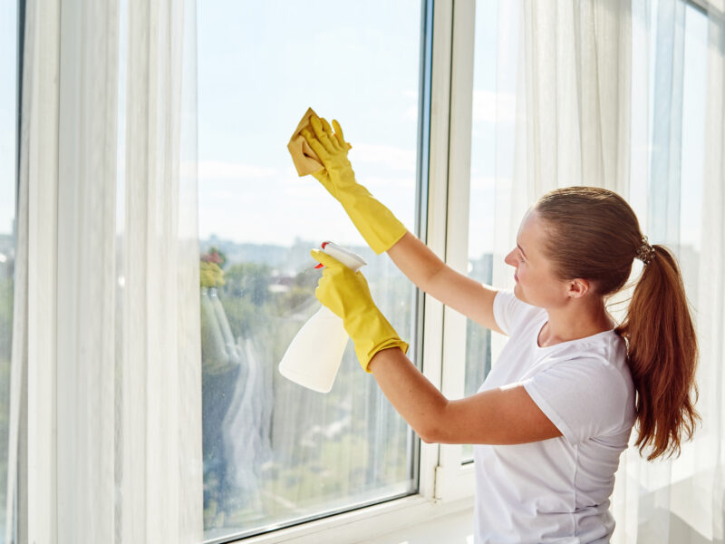 Woman,In,White,Shirt,And,Yellow,Rubber,Gloves,Cleaning,Window